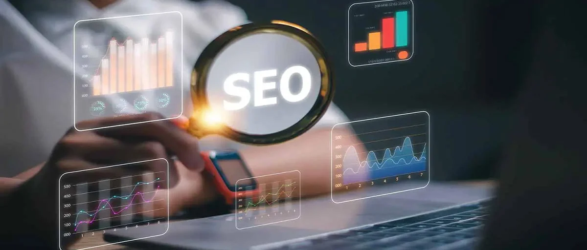 Tasarım- bilgisayar başında biri; elinde camında "SEO" yazan bir büyüteç tutuyor, havada da dijital grafikler asılı