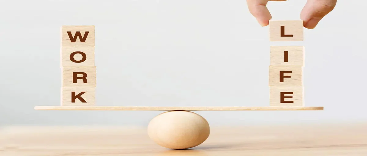 Bir topun üzerindeki tahtanın iki yanında dengede duran bloklar; sağdaki blokların üzerindeki harflerden "LIFE", soldakilerden ise "WORK" kelimesi meydana geliyor.