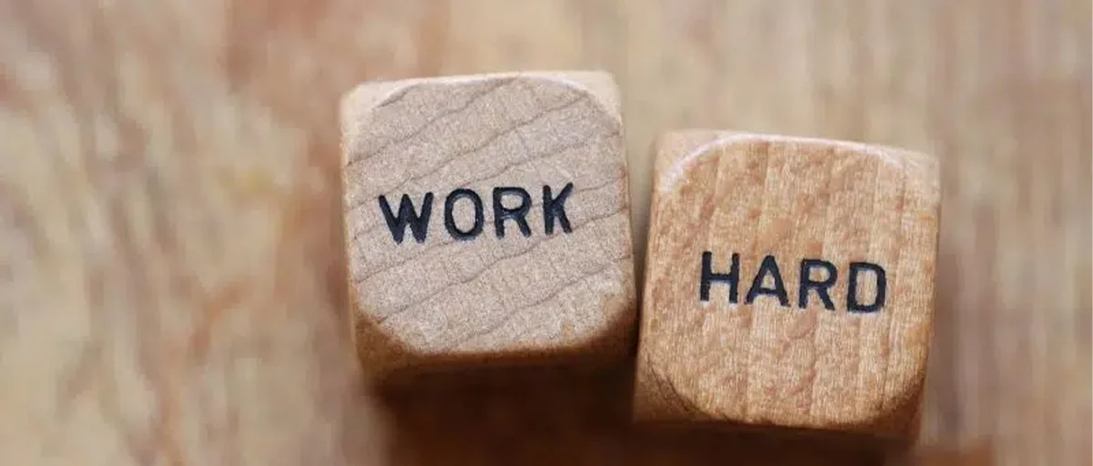 Birinin üzerinde "Work", diğerinde "Hard" yazan, yan yana koyulmuş iki tahta küp