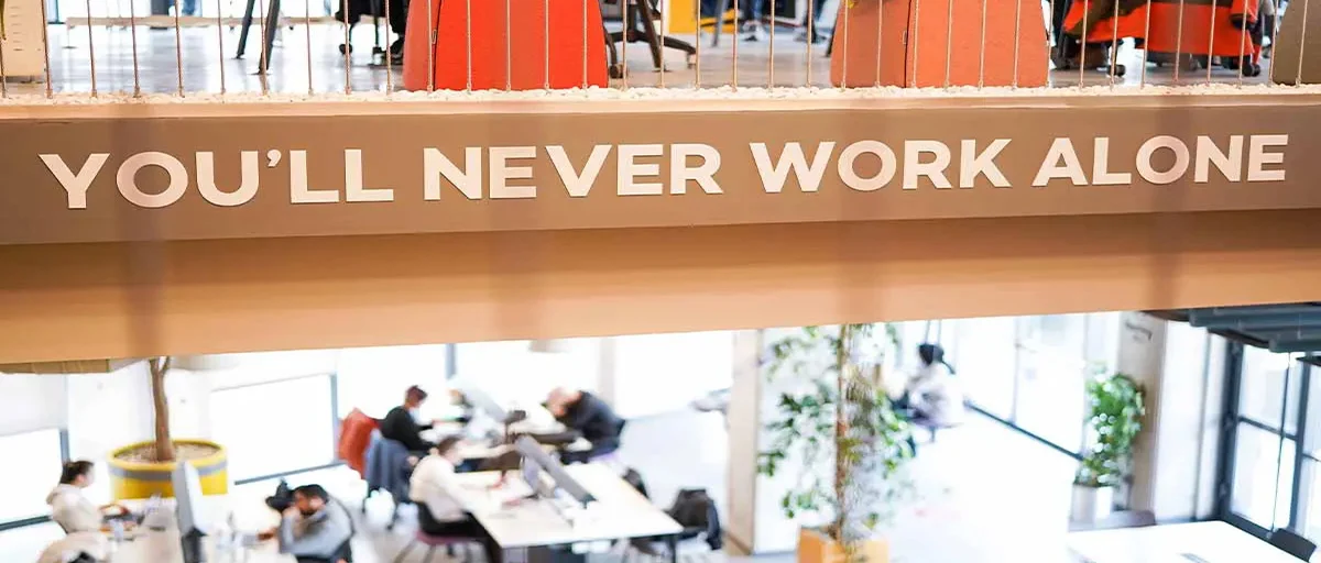Workinton ortak çalışma alanı; ofisteki "You'll Never Work Alone" yazısı ön plana alınmış
