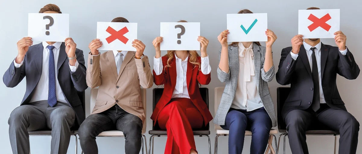 iş görüşmesi bekleyen adaylar; ellerinde üzerlerinde "?", "X" ve olumlu anlamda "check" işareti olan kartlar